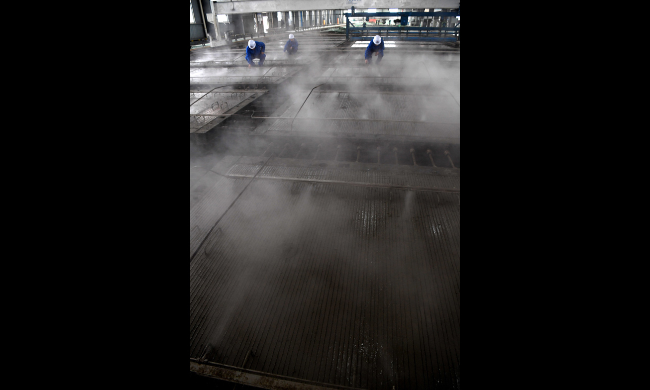 據(jù)悉，CRTSⅢ型先張法預(yù)應(yīng)力混凝土軌道板是我國自主研發(fā)、具有完全自主知識產(chǎn)權(quán)、實(shí)現(xiàn)技術(shù)創(chuàng)新的一項(xiàng)重大科技成果，是我國高速鐵路無砟軌道技術(shù)實(shí)現(xiàn)國產(chǎn)化的重要標(biāo)志。圖為中鐵十一局橋梁公司江西豐城制板場職工在運(yùn)用自主研發(fā)的智能霧化養(yǎng)護(hù)系統(tǒng)對CRTSⅢ型先張法軌道板進(jìn)行養(yǎng)護(hù)。（新華社記者 宋振平 攝）