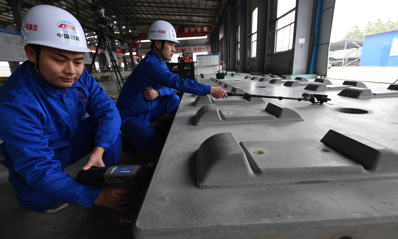 2018年1月22日，王偉（左）用手持式噴碼槍在給CRTSⅢ型先張法軌道板進(jìn)行激光打碼。（新華社記者 宋振平 攝）