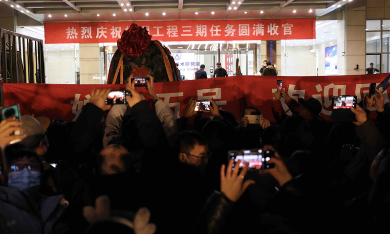 12月17日晚，在完成必要的地面處理工作后，嫦娥五號返回器被空運至北京并正式回到“出生地”——中國航天科技集團五院。按計劃，回收后的嫦娥五號返回器將取出樣品容器及搭載物。國家航天局將擇機舉行交接儀式，正式向地面應用系統移交月球樣品，我國首次地外天體樣品儲存、分析和研究相關工作也將隨之啟動。圖為當晚，在北京中國航天科技集團五院，人們在歡迎嫦娥五號返回器回到出生地。（新華社記者 金立旺 攝）