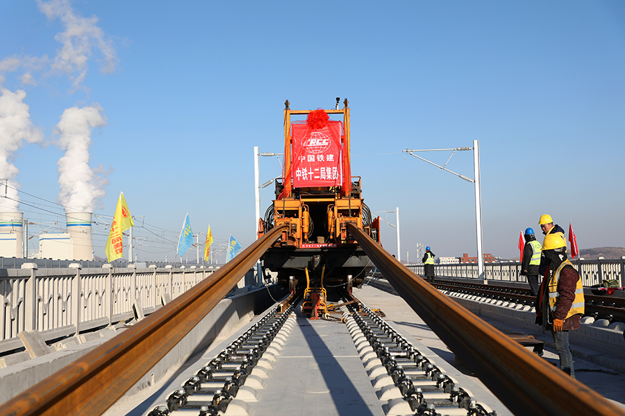 日前，朝凌高鐵無砟道床段落鋼軌全線鋪通。朝凌高鐵自京沈高鐵遼寧朝陽站引出，經遼寧朝陽市、北票市、錦州市后接入京哈鐵路秦沈段（秦沈客專）的凌海南站，建設里程105公里，設計時速350公里，是我國東北地區高速鐵路網的重要組成部分。圖為中國鐵建所屬中鐵十二局建設者操作軌道牽引車進行最后一組500米長鋼軌鋪設。（李煜 攝）