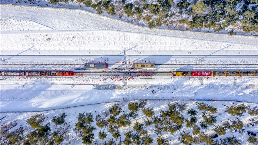 受“拉尼娜”氣候影響，今年當(dāng)?shù)貥O端低溫進(jìn)一步加強(qiáng)，惡劣的環(huán)境給機(jī)務(wù)運(yùn)輸帶來(lái)巨大挑戰(zhàn)，項(xiàng)目部機(jī)運(yùn)施工使用的是東風(fēng)4B型內(nèi)燃機(jī)車，啟機(jī)時(shí)油水溫度不能低于20攝氏度，如果機(jī)車因機(jī)械或電器故障停機(jī)，3小時(shí)內(nèi)不能恢復(fù)，整個(gè)水循環(huán)系統(tǒng)將凍結(jié)，直接損失在80萬(wàn)元以上。為了解決這一難題，項(xiàng)目部在鋪軌基地建起了機(jī)車恒溫庫(kù)，使用煤炭鍋爐為車庫(kù)增溫，經(jīng)過(guò)保暖的機(jī)車，打溫時(shí)間由原來(lái)的24小時(shí)縮短到1小時(shí)，1周只需打溫一次。機(jī)車恒溫庫(kù)投入使用以來(lái)，為項(xiàng)目節(jié)約燃油約200多萬(wàn)升。圖為中鐵十四局和對(duì)線施工的鋪軌機(jī)組順利“會(huì)師”。
