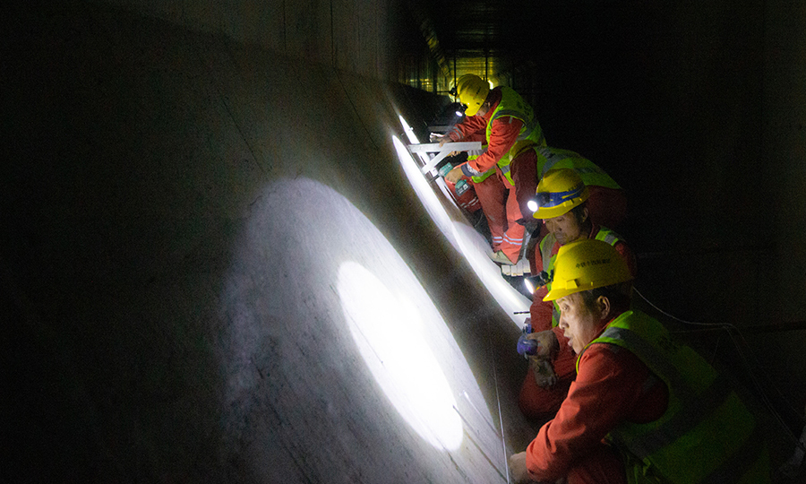 穿黃隧道工程裝飾裝修工程分為隧道暗埋段、隧道盾構段。盾構段采用超大斷面盾構法施工，盾構管片外徑為15.2米，管片內徑13.9米，由中國鐵建所屬中鐵十四局電氣化公司承擔全部裝飾裝修施工任務。圖為隧道內的施工工人。（范成濤 攝）