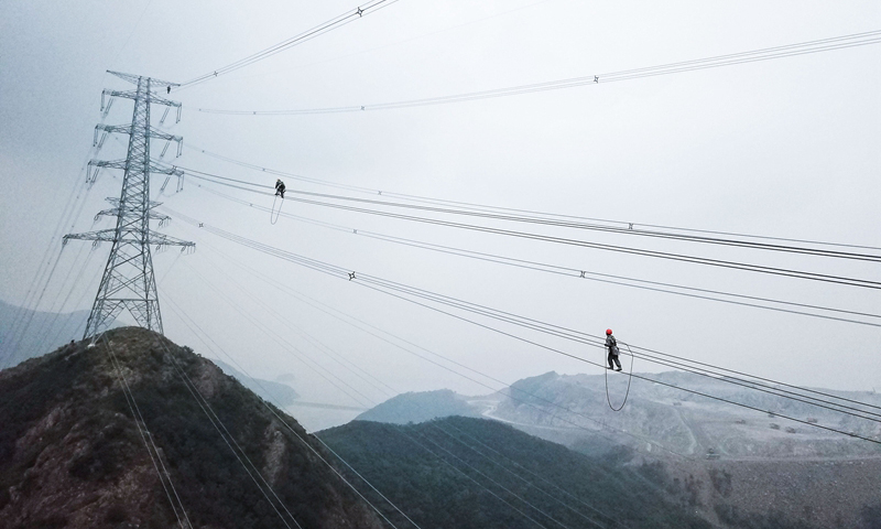 圖為10月23日，檢修人員在跨海輸電高塔上進行走線工作。（新華社記者 徐昱 攝）