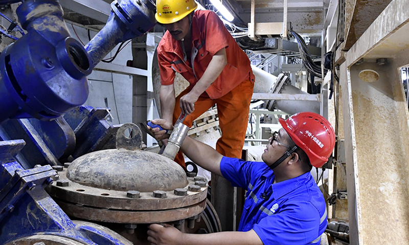 2020年4月份以來，盾構機從掘進460環開始出現震動、異響，經巡視和分析發現，竟然有一些石塊“躲”過了盾構機前端破碎機的“嘴巴”，流入出槳管道，卡死泥漿泵。這些石塊質地堅硬，鈣質結核，強度為45兆帕，相當于高鐵橋墩混凝土的強度，最大的一塊有75厘米長，重達150斤，他們果斷采取在泥漿管前加采石箱的方法將石頭阻擋在泥漿泵前面。圖為盾構機維保人員對盾構機上加裝的采石箱進行檢查。