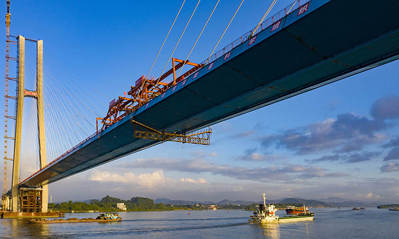 大橋橋址環境復雜，傳統孔跨布置方案無法滿足通航及防洪要求。設計團隊創新性采用非對稱布置混合梁斜拉橋，為國內同類型的橋梁建設提供了寶貴的經驗。針對貨運鐵路荷載重、速度低的特點，設計寬跨比近1/30，橋面布置更為緊湊，進一步提升了貨運鐵路斜拉橋的經濟性。圖為合龍現場。（金偉 攝）