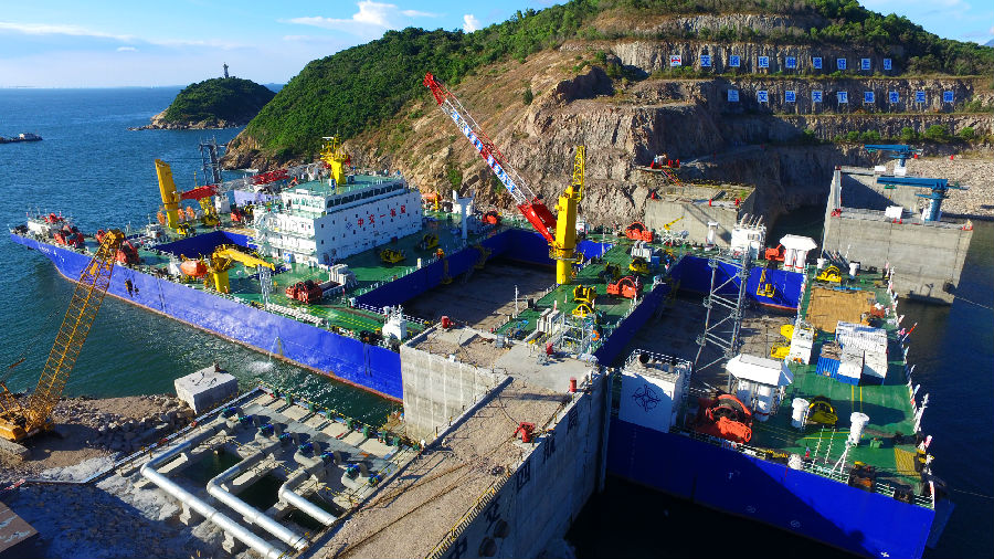 深中通道海底隧道部分是世界首例雙向八車道鋼殼海底沉管隧道，E2管節(jié)為首個(gè)標(biāo)準(zhǔn)管節(jié)，長165米，寬46米，高10.6米，重約7.7萬噸。比不久前完成安裝的E1管節(jié)比41.5米、重量超出2萬噸。標(biāo)準(zhǔn)管節(jié)E2在施工工藝、安裝條件等方面面臨多個(gè)“第一次”：為保證作業(yè)安全，中交集團(tuán)所屬中交一航局科研團(tuán)隊(duì)對E2管節(jié)與一體船的連接進(jìn)行重新核算。圖為施工現(xiàn)場。