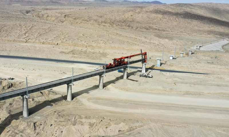 目前，國家重點工程——格庫鐵路（青海格爾木至新疆庫爾勒）新疆段按照節點有序推進鋪架作業，橋梁和軌排已生產完畢，焊軌工作全面展開。圖為7月18日，中鐵一局的施工人員跨315國道進行架梁作業。（新華社記者 丁磊 攝）