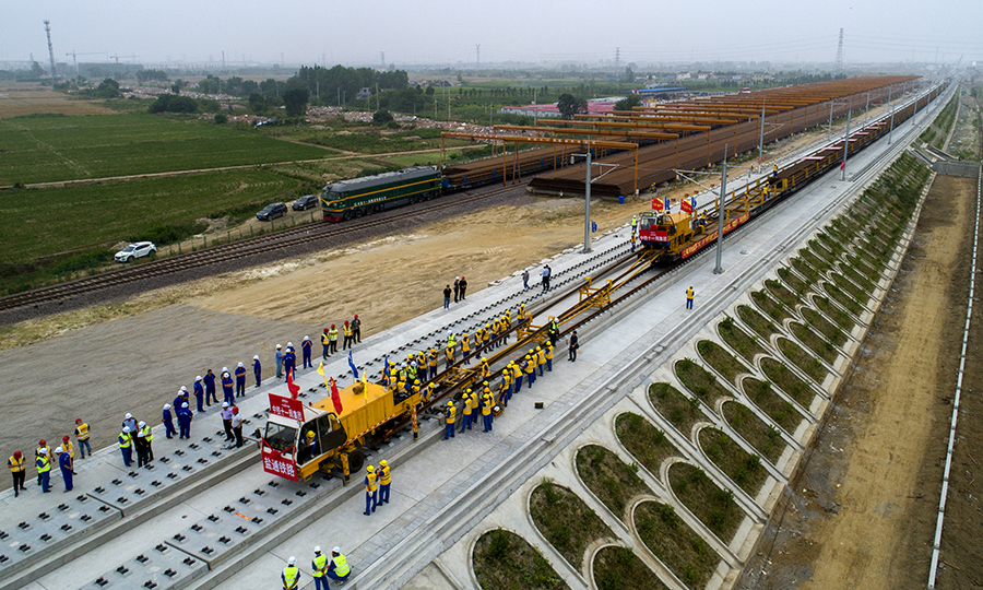6月12日，在江蘇省東臺(tái)市的鹽通高鐵東臺(tái)站外施工現(xiàn)場(chǎng)，中國(guó)鐵建所屬中鐵十一局鋪軌機(jī)牽引著第一組500米長(zhǎng)鋼軌平穩(wěn)地落在無(wú)砟道床上，標(biāo)志著我國(guó)“八縱八橫”高鐵網(wǎng)沿海通道重要組成部分的鹽通高鐵建設(shè)整體從線(xiàn)下施工轉(zhuǎn)入線(xiàn)上軌道鋪設(shè)階段。圖為鹽通高鐵全線(xiàn)首鋪現(xiàn)場(chǎng)。（劉連強(qiáng) 攝）