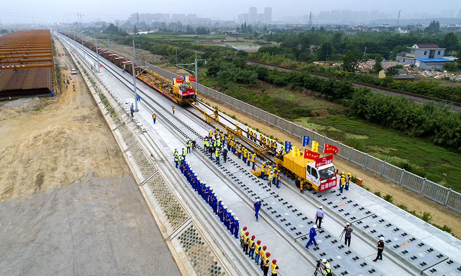 鹽通高鐵位于鹽城、南通境內(nèi)，是國(guó)家“八縱八橫”高鐵網(wǎng)中沿海通道的重要組成部分，全線(xiàn)設(shè)鹽城、大豐、東臺(tái)、海安、如皋南和南通西6座車(chē)站，正線(xiàn)全長(zhǎng)156.6公里，設(shè)計(jì)時(shí)速350公里。中鐵十一局承擔(dān)著全線(xiàn)軌道鋪設(shè)和121組道岔的鋪設(shè)任務(wù)。圖為鹽通高鐵全線(xiàn)首鋪現(xiàn)場(chǎng)。（劉連強(qiáng) 攝）