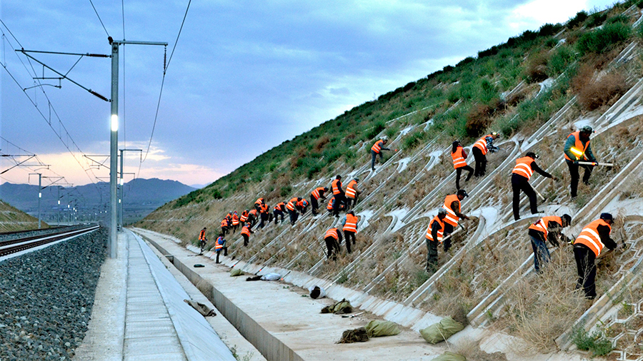 在中鐵二十局承建的崇禮鐵路二標施工現場一派繁忙。彼時，項目參建者正克服既有線施工安全風險大、氣候環境惡劣等困難，補種苗木4萬株，為綠色生態冬奧奠定堅實基礎。圖為參建工人對路基邊坡進行綠植施工。（曲志忠 攝）