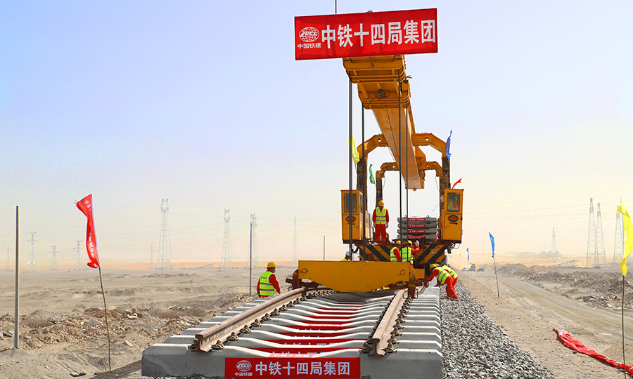 和(田)若(羌)鐵路位于新疆維吾爾自治區南部和田地區和巴音郭楞蒙古自治州境內，是國家《中長期鐵路網規劃》中的重要鐵路干線。線路從南疆鐵路和田站引出，經洛浦、策勒等縣市，東至巴州若羌縣，全長825公里，為單線鐵路，設計時速120公里，為客貨兩用鐵路線。建成后將與在建的格庫鐵路組成新疆第三條東西向交通大干線和國際大通道，并與格庫鐵路、南疆鐵路相連在塔里木盆地周邊形成一條環形鐵路網，也將是世界首條繞沙漠環形鐵路網。圖為首組軌排精準落位。