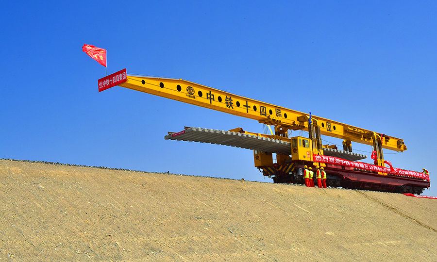 其中，中鐵十四局承擔著和若鐵路PJS2標段2312片T梁的預制、架設和535公里鋪軌等任務，鋪軌里程占全線總長的65%。沿線氣候干旱，資源匱乏，風沙天氣繁多，晝夜溫差大，穿越無人區,軌料的運輸距離也長達700多公里。項目部調集具有沙漠施工經驗的管理和施工人員，借鑒額哈鐵路建設經驗，成立課題攻關小組，科學組織，超前謀劃，采用邊臨建施工，邊組織設備進場的方案保證進度。圖為鋪軌現場。