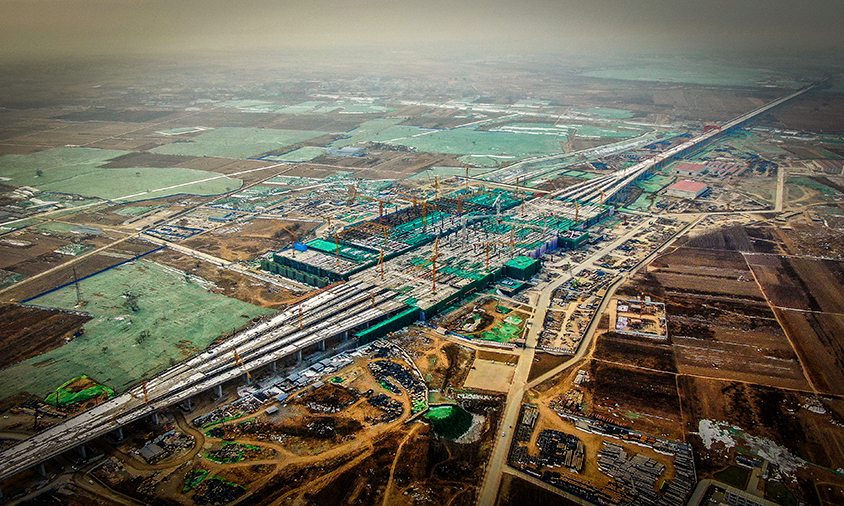 由中國鐵建所屬中鐵十二局參建的京雄城際鐵路雄安站房項(xiàng)目是雄安新區(qū)第一個(gè)開工的重大交通建設(shè)項(xiàng)目。目前該項(xiàng)目正在進(jìn)行上部鋼結(jié)構(gòu)作業(yè)和下部架體拆除，即將轉(zhuǎn)入站房?jī)?nèi)部裝飾、機(jī)電安裝作業(yè)，站房預(yù)計(jì)于今年年底建成。圖為雄安站施工現(xiàn)場(chǎng)。（任雙歡 攝）