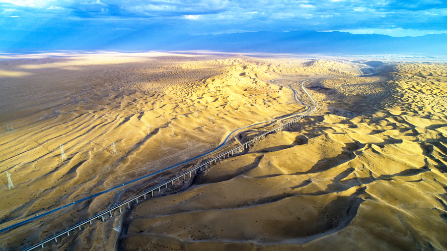 敦格鐵路北起甘肅省敦煌市敦煌站，南至青海省格爾木市格爾木站，全長(zhǎng)616.79公里，其中新建線路509.02公里，設(shè)計(jì)時(shí)速120公里，是國(guó)鐵I級(jí)電氣化單線鐵路。圖為沙山溝特大橋高空俯拍。（金偉 攝）