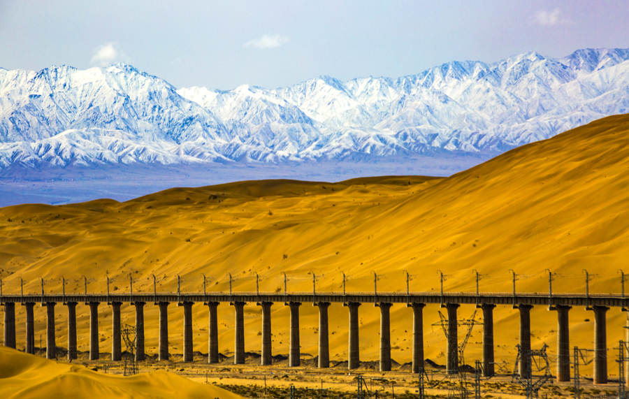 自2012年底敦格鐵路開工建設(shè)以來(lái)，中國(guó)鐵建科學(xué)組織、優(yōu)化施工方案、合理安排作業(yè)時(shí)間，先后順利完成了全線多個(gè)重點(diǎn)控制性工程施工。在當(dāng)金山隧道施工中，建設(shè)者大力進(jìn)行科技創(chuàng)新，攻克高寒缺氧等難題，創(chuàng)造了我國(guó)隧道獨(dú)頭掘進(jìn)最長(zhǎng)、高原隧道施工通風(fēng)距離最長(zhǎng)的紀(jì)錄。圖為沙山溝特大橋與沙山、雪山融為一體，美輪美奐。（金偉 攝）