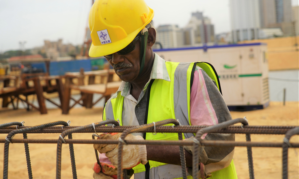 隨著科倫坡港口城填海造地工程完工以及市政設施建設陸續啟動，這座由中國和斯里蘭卡在“一帶一路”倡議下聯合開發的南亞新城邁入發展新階段。目前中斯正在攜手推動港口城的招商工作。根據雙方愿景，港口城內將推行一系列惠商措施以吸引全球投資者，為斯里蘭卡打造開放經濟新高地。圖為7月22日，一名當地工人在斯里蘭卡科倫坡港口城景觀水道區域為運河護岸鋼筋籠綁鋼筋。（新華社記者 唐璐 攝）