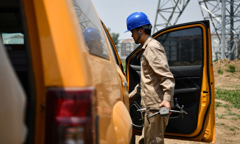 圖為6月24日，電力工人從車上取出無人機準備開始巡檢工作。（新華社記者 李然 攝）