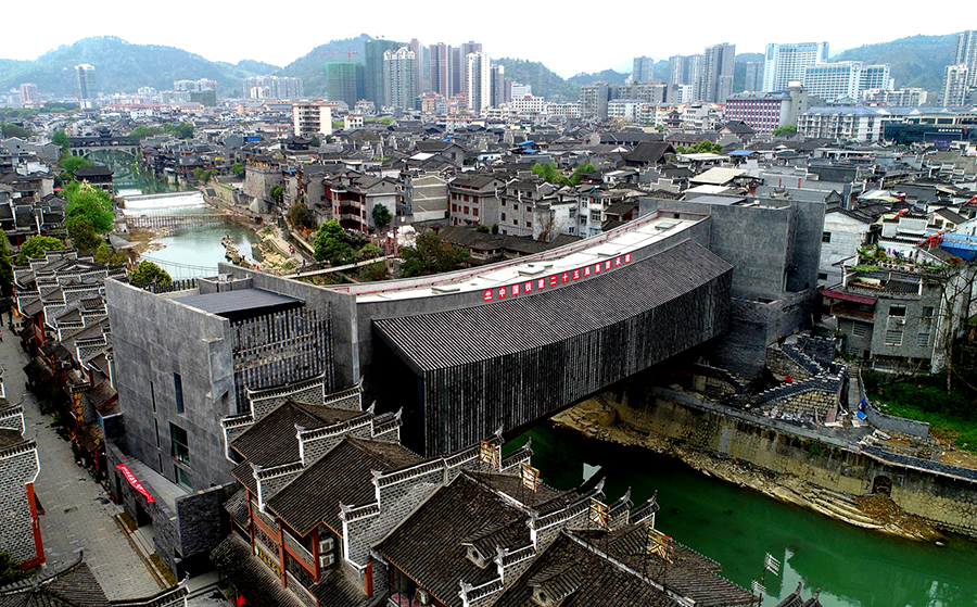 吉首美術館橋位于國家4A級景區湖南省吉首市乾州古城內，橋梁總建筑面積約3500平方米。該橋采用“橋館合一”的設計理念，全橋由混凝土系桿拱橋及雙層鋼桁梁簡支梁橋兩座橋疊加組成，結構復雜，共包括3個部分：上層混凝土橋作為小型展覽廳，鋼桁梁頂部橋面作為大型展覽廳，鋼桁梁下層橋面為公共人行橋。這種上下兩個展廳和公共人行橋“三合一”的造型結構，屬亞洲首例。圖為美術館橋側景。