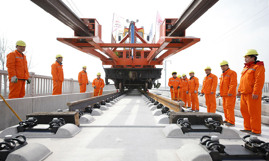 作為商合杭高鐵全線最大鋪軌基地，中鐵十八局五公司管區(qū)內(nèi)古城集鋪軌基地可同時(shí)存儲(chǔ)960根500米鋼軌，滿足240公里鋪軌需求。軌道鋪設(shè)由古城東站分別向河南商丘與安徽阜陽兩個(gè)方向進(jìn)行，日鋪軌可達(dá)6公里。作為我國“八縱八橫”路網(wǎng)規(guī)劃和京九高鐵的重要組成部分，商合杭全線預(yù)計(jì)2020年建成運(yùn)營，將與長三角城際軌道交通圈形成互聯(lián)互通。（徐輝 攝）