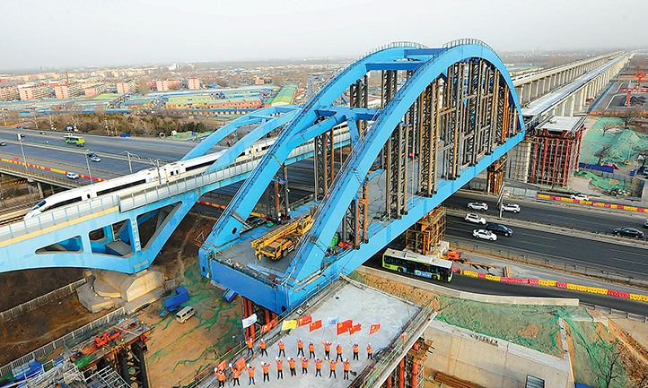 春節(jié)期間，由中國(guó)鐵建所屬中鐵十二局承建的京雄城際鐵路黃固村特大橋跨京開(kāi)高速公路一體式雙線簡(jiǎn)支鋼箱拱橋頂推順利完成。該橋跨度為114 米，重達(dá)3100 噸，是京雄鐵路全線重點(diǎn)控制性工程。在歷時(shí)7天的頂推施工中，中鐵十二局制定了“毫厘監(jiān)控，穩(wěn)健頂推”等嚴(yán)謹(jǐn)?shù)陌踩胧_保了春運(yùn)期間京開(kāi)高速公路安全暢通。（賈鵬翼 攝）