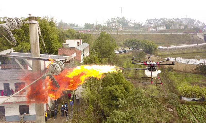 圖為1月16日，噴火清障無人機(jī)在國網(wǎng)重慶永川供電公司無人機(jī)班操作手的控制下，對重慶市永川區(qū)大安街道小坎村10千伏隆安線16號桿處的一個馬蜂窩進(jìn)行噴火清除。（新華社記者 劉潺 攝）