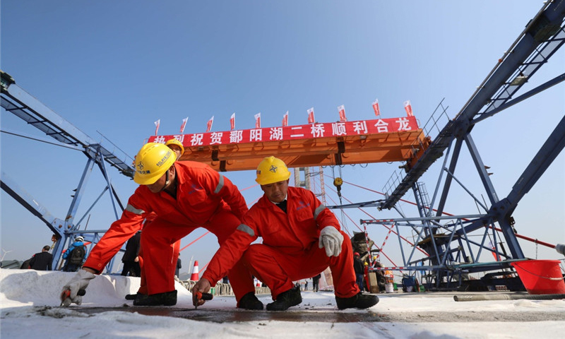 圖為11月28日，兩名工人在鄱陽湖二橋橋面上進(jìn)行收面施工。新華社發(fā)（韓俊烜 攝）