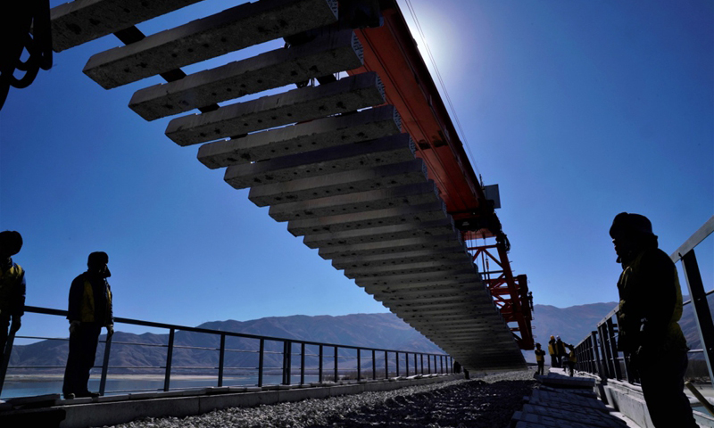 11月26日，在貢嘎雅魯藏布江特大橋上，第一組長25米的軌排精準落下。這標志著川藏鐵路拉林段第一座跨江大橋——貢嘎雅魯藏布江特大橋開始鋪軌架梁，拉林鐵路順利邁出了跨越雅江的第一步。圖為中鐵十一局施工人員在川藏鐵路拉林段貢嘎雅魯藏布江特大橋上鋪軌。（新華社記者 覺果 攝）