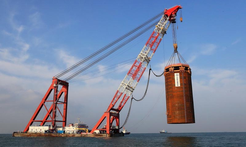 港珠澳大橋通車在即。從2009年12月15日，港珠澳大橋正式開工建設，到2018年2月，港珠澳大橋主體工程通過交工驗收，具備通車試運營條件，9年間，潮起潮落、寒來暑往，數以萬計的建設者在伶仃洋上造橋，在大海深處“穿針”，構筑起全長55公里的世界級跨海通道。圖為2011年9月11日，港珠澳大橋島隧工程西人工島最后一個鋼圓筒振沉成功，西人工島順利成島。新華社發（港珠澳大橋局提供）