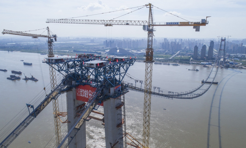 楊泗港長江大橋是一座雙塔雙層地錨式鋼桁梁公路懸索橋，主跨1700米，一步跨越長江。建成后將成為世界上跨度最大的雙層懸索橋。圖為6月25日，無人機航拍的楊泗港大橋南岸施工現場。（新華社記者 肖藝九 攝）