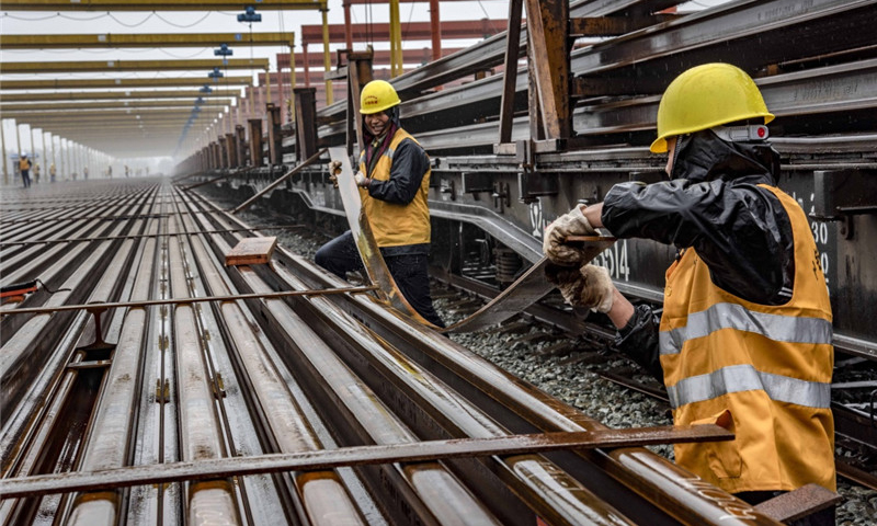 隨著漢十高鐵進(jìn)入緊張的攻堅(jiān)階段，承擔(dān)漢十高鐵全線鋪軌施工的中鐵十一局三公司已經(jīng)全面展開(kāi)長(zhǎng)軌運(yùn)輸、存儲(chǔ)、焊接等工作。目前，該公司漢十高鐵棗陽(yáng)鋪軌基地已經(jīng)存儲(chǔ)長(zhǎng)軌262.5公里，為漢十高鐵全線長(zhǎng)軌鋪設(shè)奠定了基礎(chǔ)。圖為5月5日，中鐵十一局職工在漢十高鐵棗陽(yáng)鋪軌基地存軌區(qū)安放扁鐵，為堆碼500米長(zhǎng)軌做準(zhǔn)備。（新華社記者 杜華舉 攝）