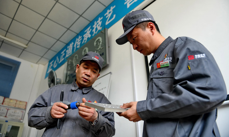 4月27日，周晶輝（左）與徒弟臧鐵軍一起研究改進工作中使用的工具。（新華社記者 張楠 攝）