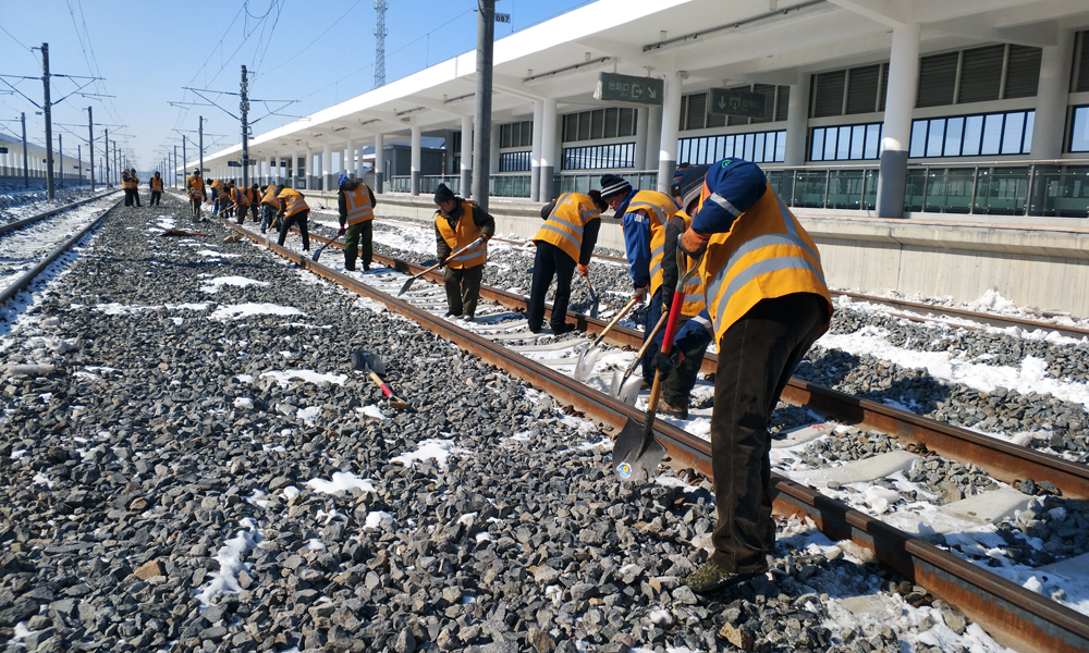 精調小車在鋼軌上徐徐前行，技術人員仔細記錄著顯示屏幕上的數據。不遠處，工作人員正在清理線路上的積雪，保障精調施工的順利進行。
