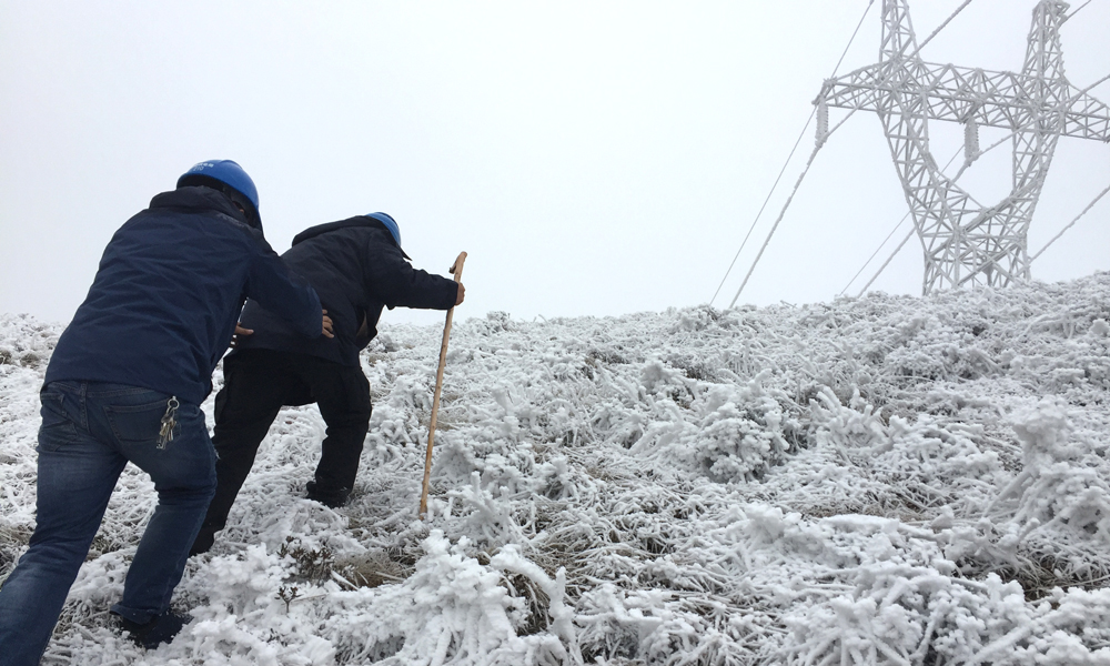 圖為南方電網云南公司昭通供電局近60歲的老員工帶著90后徒弟艱難的上山巡線中。（李建 攝）