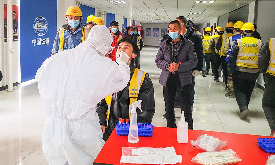 近日，剛從中國鐵建所屬中鐵十四局電氣化公司天津地鐵6號線職工活動室（臨時檢測室）走出的一線工人王小富向家人報平安，剛剛收到核酸檢測報告為陰性，項目部為員工發放口罩，免費組織做核酸檢測。圖為為工人進行核酸檢測。