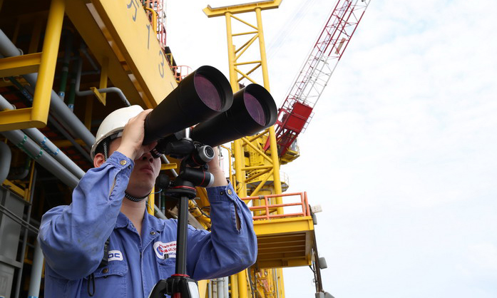 海管檢測(cè)系統(tǒng)上線后，氣田工作人員目視巡檢海管制度仍同時(shí)執(zhí)行。圖為氣田工作人員用高倍望遠(yuǎn)鏡巡視海面。