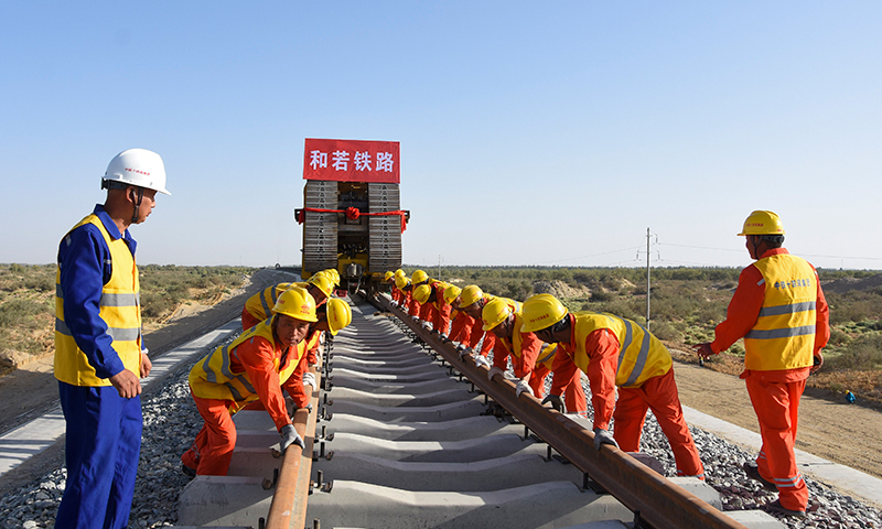 9月27日上午，隨著最后兩條鋼軌在道床上鋪設(shè)完成，作為環(huán)塔克拉瑪干沙漠鐵路“最后一公里”的和若鐵路全線鋪軌貫通，為2022年開通運營奠定堅實基礎(chǔ)。中鐵十四局工人正準備將鋼軌合龍。圖為中鐵十四局工人正準備將鋼軌合龍。(新華社記者 顧煜 攝)