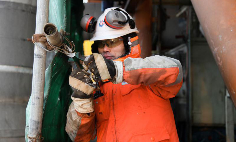 圖為錦州20-2氣田操作班長商聞賢戰風斗雪，在風雪中矗立了近一個小時，對擋風帆布進行加固，確保設備運行穩定。