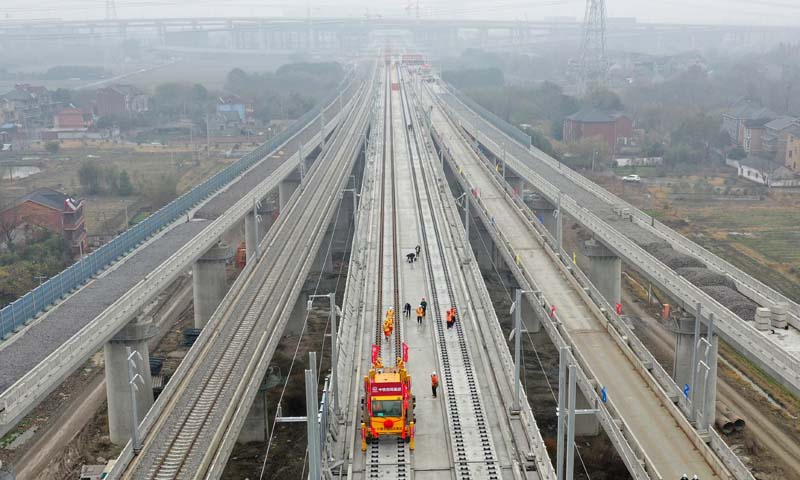 湖杭鐵路設(shè)計(jì)時(shí)速350公里，是“軌道上的長(zhǎng)三角”重要節(jié)點(diǎn)工程和2022年杭州亞運(yùn)會(huì)重點(diǎn)配套工程。圖為施工人員在湖杭鐵路上進(jìn)行鋪軌作業(yè)（無(wú)人機(jī)照片）。（新華社記者 黃宗治 攝）