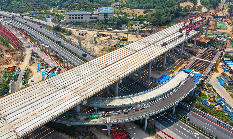 東部過境高速起于蓮塘口岸，途經羅湖區、龍崗區、坪山區，終于金錢坳立交，與深汕、惠鹽高速公路相交。圖為架梁機在深圳東部過境高速簡龍立交橋進行鋪架作業（無人機照片）。