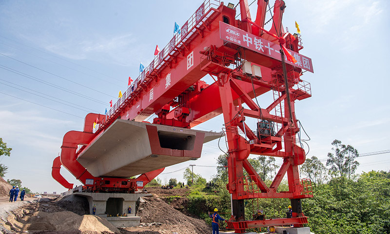近日，在由中鐵十一局集團(tuán)承建的渝昆高鐵重慶段建設(shè)現(xiàn)場，首榀重約830噸的大型箱梁精準(zhǔn)架設(shè)在金家灣1號中橋上，標(biāo)志著渝昆高鐵重慶段正式拉開架梁序幕。圖為在渝昆高鐵重慶段建設(shè)現(xiàn)場，架橋機(jī)在進(jìn)行首榀箱梁架設(shè)作業(yè)。