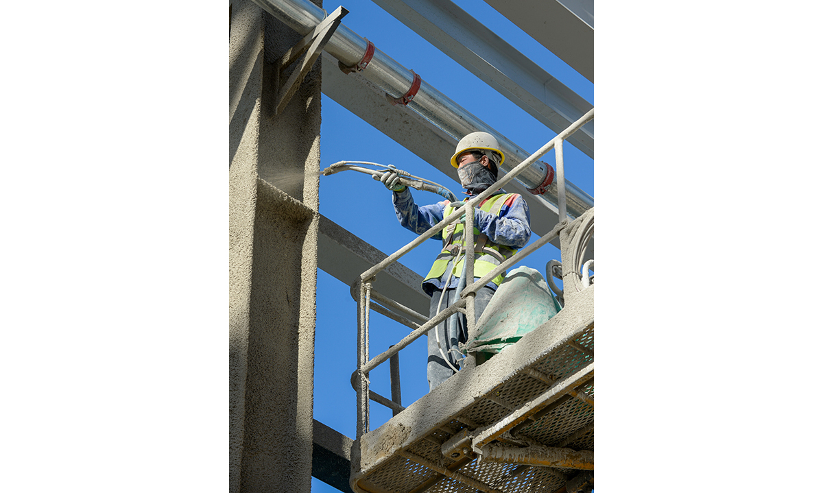 新疆塔城重點開發開放試驗區一處正在建設的智慧物流倉庫內，工人對墻體進行噴灑作業（5月18日攝）。新華社記者 高晗 攝