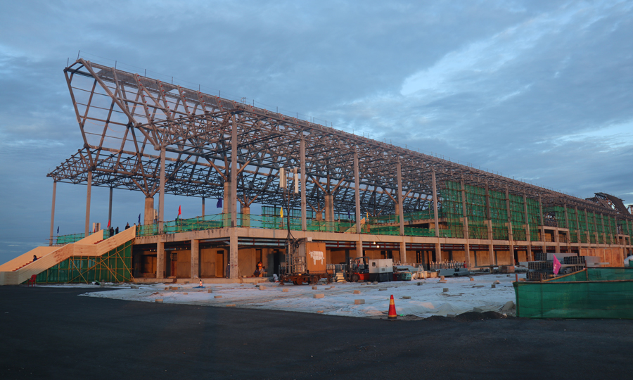 暹粒吳哥國際機(jī)場項(xiàng)目飛行區(qū)跑道長3600米、寬45米，是飛行區(qū)的主體工程。跑道混凝土工程自今年1月16日正式啟動以來，克服疫情、高溫、降雨、地材緊張、海運(yùn)周期長等不利因素影響，積極引進(jìn)滑模攤鋪機(jī)施工，顯著提升了道面混凝土的施工質(zhì)量和效率，歷時(shí)125天，完成7萬立方米的混凝土澆筑，提前10天完成節(jié)點(diǎn)任務(wù)。圖為機(jī)場航站樓項(xiàng)目施工現(xiàn)場。