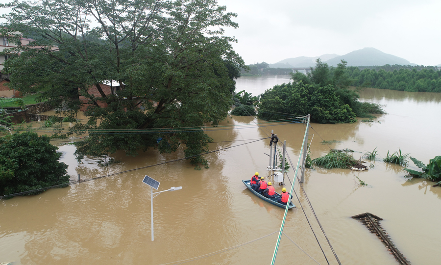 6月15日，隨著2022年“北江一號”洪水過境，廣東清城區源潭鎮轄區內大燕河水位不斷升高，導致源潭鎮老窯村部分房屋被洪水浸泡。南方電網廣東清遠清城供電局源潭供電所工作人員劃船前往村中了解居民受災情況，并檢查安全隱患采取緊急停電措施，保障村民們汛期用電安全。（覃軒-攝）