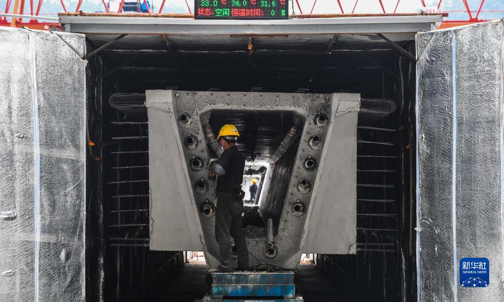 黃茅海跨海通道橫跨珠江口崖門入?？邳S茅海水域，連接珠海高欄和江門臺山，線路全長約31公里，預計2024年建成通車。圖為10月18日，工人對一片剛完成智能蒸養(yǎng)的預制箱梁進行銜接面打毛。完成混凝土澆筑的預制箱梁需要進行蒸養(yǎng)作業(yè)，以增加結構強度。新華社記者 劉大偉 攝