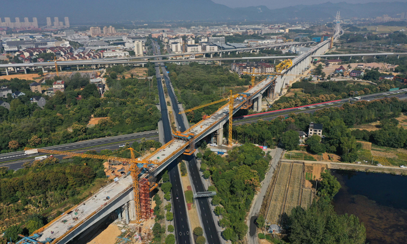 10月20日，由中鐵上海工程局承建、位于浙江杭州桐廬縣境內的杭溫鐵路二期工程跨杭黃鐵路特大橋長達390米的連續梁順利合龍，這是杭溫鐵路二期工程實現合龍的最大跨度連續梁。圖為10月20日拍攝的杭溫鐵路二期工程跨杭黃鐵路特大橋完成合龍的最大跨度連續梁（無人機照片），該連續梁同時上跨杭新景高速公路和桐廬縣鳳川大道。新華社記者 黃宗治 攝