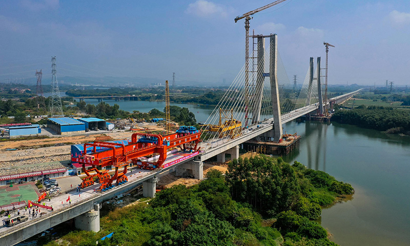 10月25日，中鐵五局承建的廣汕鐵路鋪架施工最后一孔900噸箱梁成功架設在廣州增江特大橋橋墩上，標志著全線箱梁架設完成。圖為施工人員操作架橋機將最后一孔900噸箱梁成功架設在增江特大橋橋墩上（無人機照片）。新華社記者 劉大偉 攝