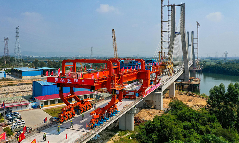 設計時速350公里的廣汕鐵路全長206.2公里，途經廣州、惠州、深汕合作區、汕尾，全線預計2023年建成通車。通車后，廣州到汕尾運行時間將由現在的2小時左右縮短至40分鐘左右，將有力助推粵東地區加快融入粵港澳大灣區。圖為10月25日，施工人員操作架橋機將最后一孔900噸箱梁成功架設在增江特大橋橋墩上（無人機照片）。新華社記者 劉大偉 攝