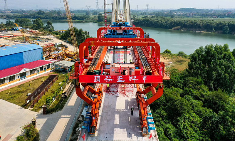 10月25日，施工人員操作架橋機將最后一孔900噸箱梁成功架設在增江特大橋橋墩上（無人機照片）。新華社記者 劉大偉 攝