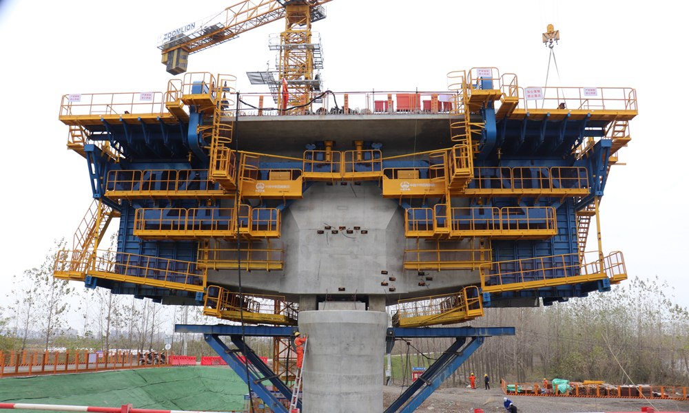 智慧造橋機由承重桿件、液壓整體模板、液壓調節、自動走行、信息化監控、鋼筋骨架整體吊裝、平臺防護等系統組成，并預留了智能蒸汽養護、自動噴淋等多功能系統安裝接口，集液壓傳動、智能操控、信息化監測技術于一體，極大解決了傳統掛籃在懸臂現澆連續梁施工中結構復雜、裝拆繁瑣等問題，大幅提高了懸臂現澆梁自動化、信息化和智能化建造水平，推廣前景廣闊。