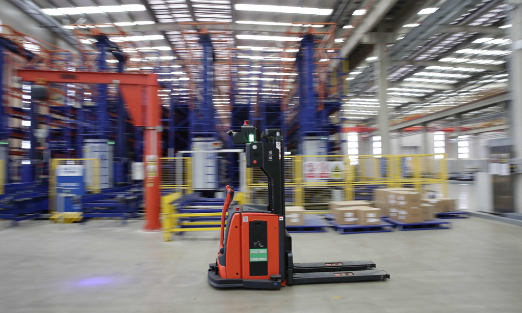 數(shù)字化智造管控系統(tǒng)（DIMS）是指揮自動(dòng)化生產(chǎn)線的大腦。在項(xiàng)目啟動(dòng)期，從DIMS發(fā)往生產(chǎn)執(zhí)行系統(tǒng)的工單總是發(fā)送失敗，生產(chǎn)一度陷入停滯。經(jīng)過一次次不懈努力，項(xiàng)目組終于完成系統(tǒng)迭代，為后續(xù)系統(tǒng)開發(fā)提供了寶貴經(jīng)驗(yàn)。圖為在基地智能倉儲(chǔ)中心，無人駕駛叉車正在作業(yè)。